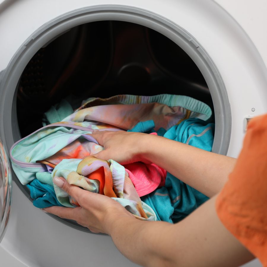 Woman putting dirty laundry into washing machine